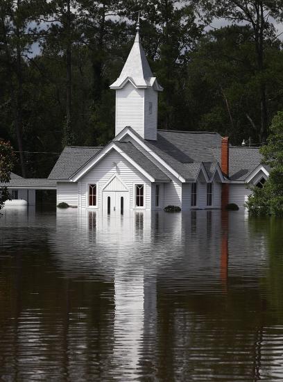 A simple, white church sits in about three feet of water.
