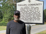 Richard Habersham stands in front of a Phillips Community welcome sign on the side of the road.