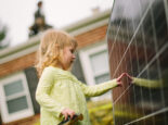 Child touching a solar panel with their hand