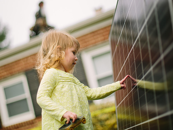 Child touching a solar panel with their hand