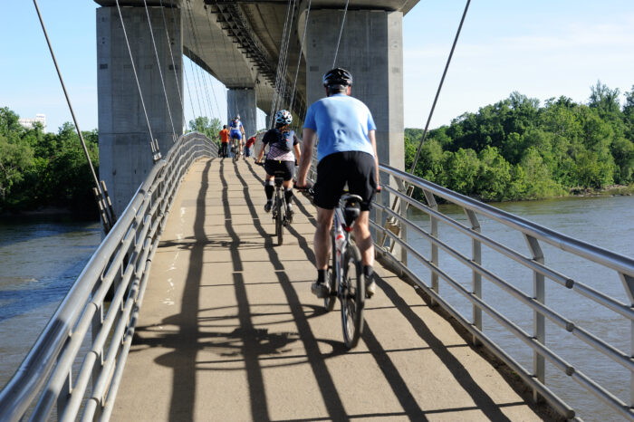 People ride bikes over a bridge over water in Richmond, Virginia.