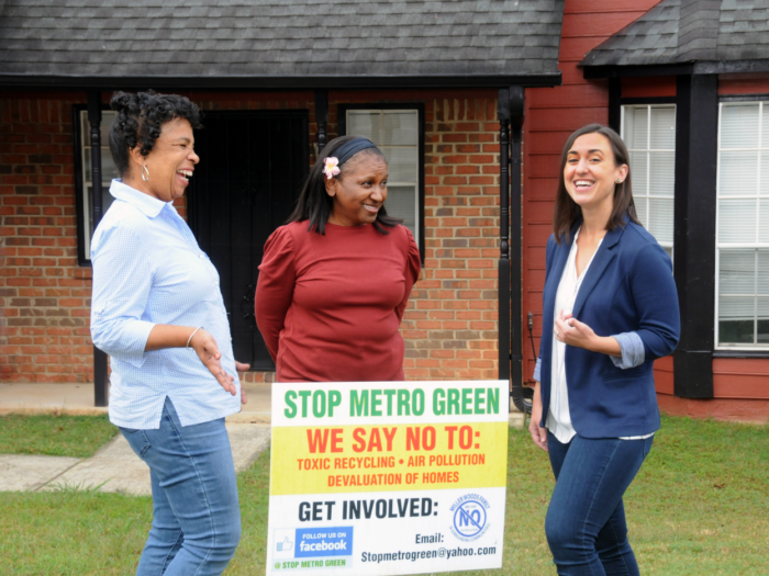 Women have a conversation while standing around a Stop Metro Green campaign sign.