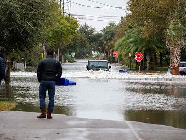 A man looks out over a heavily flooded street. Floods are a common concern in areas impacted by environmental injustice.