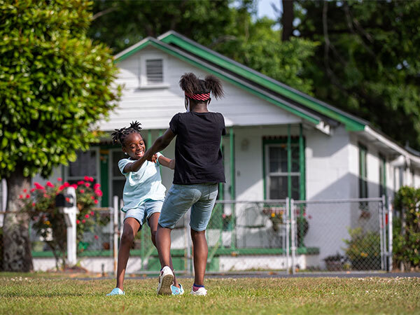 Two children playing in the front yard of a house