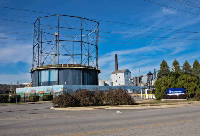 A large industrial-looking facility is pictured beside a Bluestone Coke sign.